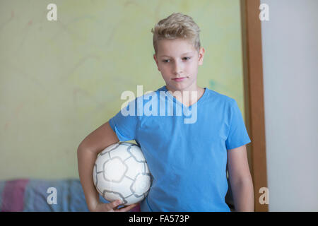 Jungen Fußball unter dem Arm hält und blickte, Freiburg Im Breisgau, Baden-Württemberg, Deutschland Stockfoto