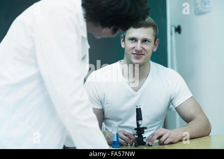 Junge Studentin mit Mikroskop und diskutieren mit seinem Lehrer in Labor, Baden-Württemberg, Deutschland Stockfoto