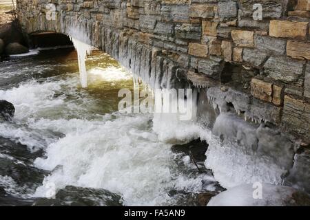 Eiszapfen hängen unter einer Brücke in Minnesota. Stockfoto