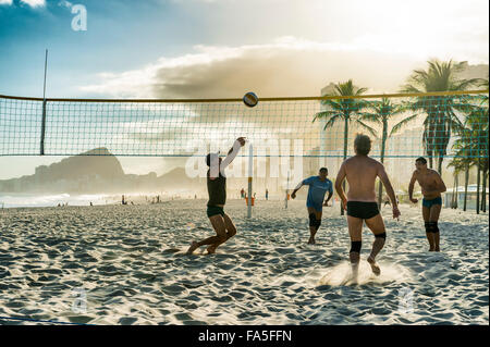 RIO DE JANEIRO, Brasilien - 30. Oktober 2015: Eine Gruppe von jungen brasilianischen Männer Volleyball spielen bei Sonnenuntergang am Strand Leme, Copacabana. Stockfoto