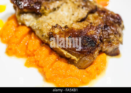 gegrilltes Fleisch mit Kürbis-Püree auf den Teller Stockfoto