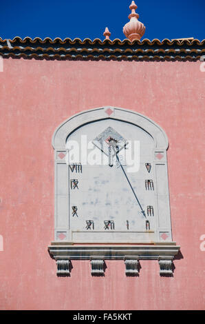 Sonnendurchflutetes Oman Ziffer Sonnenuhr an Rosa Hauswand Stockfoto