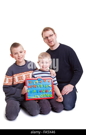 Vater lehrt seine zwei Jungs mit einer Magnettafel Stockfoto