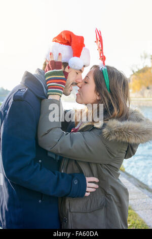 Paar in Liebe stehen im Freien mit Weihnachtsmützen Stockfoto