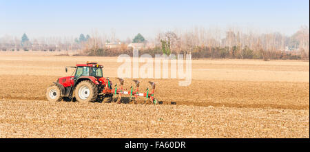 Landwirtschaftliche Arbeit, roter Traktor ein Feld pflügen Stockfoto