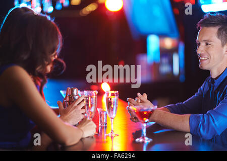 Glücklich Jüngling im Gespräch mit Mädchen beim Trinken haben im Nachtclub Stockfoto