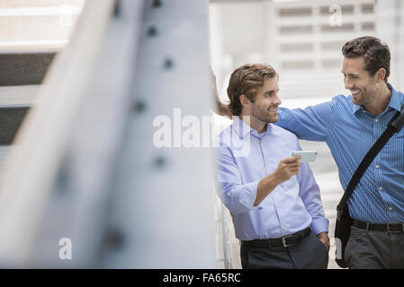 Zwei Geschäftsmänner stehend in einer städtischen Straße, mit smart-Phones. Stockfoto