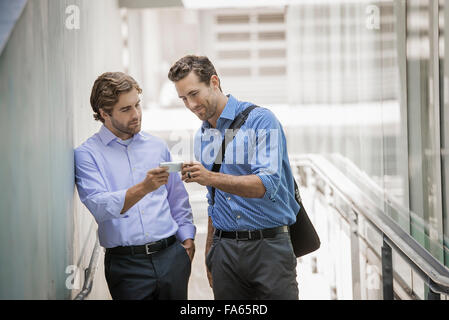 Zwei Geschäftsmänner stehend in einer städtischen Straße, mit smart-Phones. Stockfoto