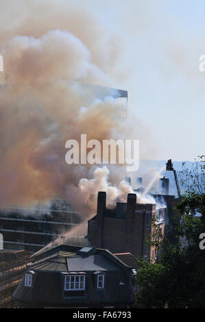 Hochhaus-Brand mit starken schwarzen Rauch und Leiter Motor Besprühen mit Wasser Stockfoto