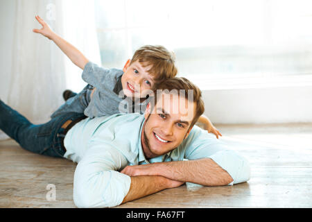 Kleiner Junge und sein Vater auf Holzboden Stockfoto