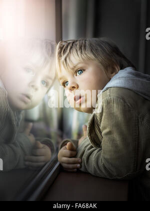 Junge Blick durch Fenster Stockfoto