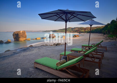 Liegestühle und Sonnenschirme am Strand morgens West Sumba, Indonesien Stockfoto