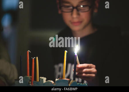 Teenager, die Beleuchtung Menorah während Hanukkah Stockfoto