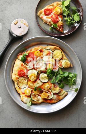 Vegetarische Pizza mit Zucchini, Zwiebeln, Cherry-Tomaten, Brunnenkresse und Mozzarella Stockfoto