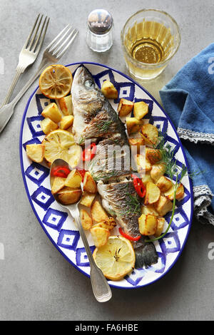 Gebackener Wolfsbarsch Fisch mit Zitrone und Kartoffeln Stockfoto