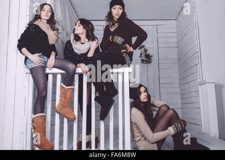 Vier stilvolle Modelle posieren auf dem Zaun sitzen Stockfoto