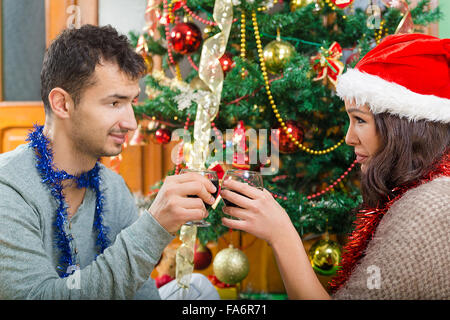 Junges Paar feiert Weihnachten zu Hause mit Gläser Wein, Silvester von zwei schönen Menschen, die trinken Wein neben Xm Stockfoto