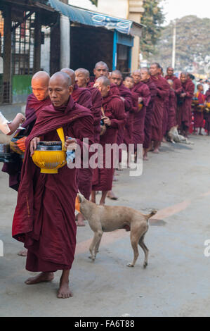 Buddhistischer Mönch in einer langen Schlange in Shwe Kyet noch Dorf in Mandalay, Myanmar, Essen in seine Almosenschale empfangen. Stockfoto