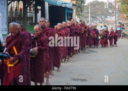 Gruppe der burmesischen Mönche auf Almosen für Lebensmittel Almosen in Shwe Kyet noch Dorf in Mandalay, Myanmar runden Schlange. Stockfoto