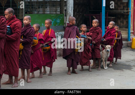 Gruppe Jugendlicher buddhistischer Mönche auf Almosen runden Schlange Essen Almosen in Shwe Kyet noch Dorf, Region Mandalay, Myanmar. Stockfoto