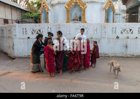 Gruppe Jugendlicher buddhistischer Mönche erhalten Essen Almosen auf Almosen Runde in Shwe Kyet noch Dorf in der Region Mandalay, Myanmar. Stockfoto