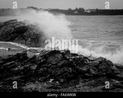 Schwarz / weiß Bild von Wellen, die über die Felsen am Strand von Rhoscolyn Stockfoto