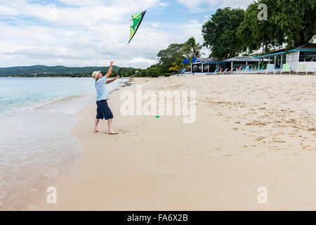 Ein älterer kaukasischen Mann wirft den Kite in der Luft einem Freund zu helfen, starten Sie das Programm auf dem Strand von St. Croix, US Virgin Islands. Cottages by the Sea Resort. Stockfoto