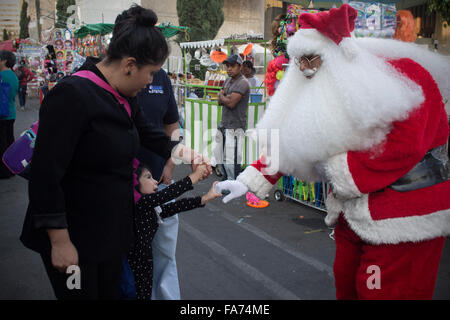 Mexico City, Mexiko. 22. Dezember 2015. Andres Santos (R), verkleidet als Weihnachtsmann, grüßt eine Mädchen in Mexiko-Stadt, Hauptstadt von Mexiko, am 22. Dezember 2015. Andres Santos, 17, fungierte als Weihnachtsmann mit Kindern darstellen, um verdienen zusätzliches Geld, um seine Ausbildung fortzusetzen. © Alejandro Ayala/Xinhua/Alamy Live-Nachrichten Stockfoto