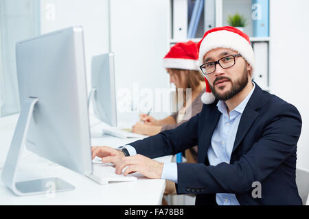 Santa Geschäftsmann Blick in die Kamera während der Arbeit am computer Stockfoto