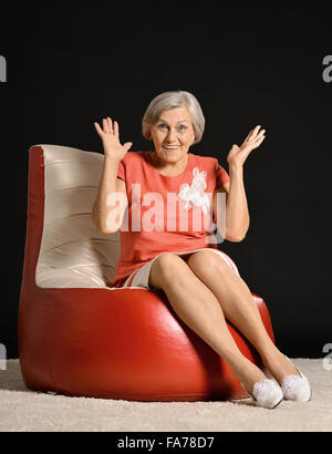 Ältere Frau sitzen auf roten Sessel Stockfoto