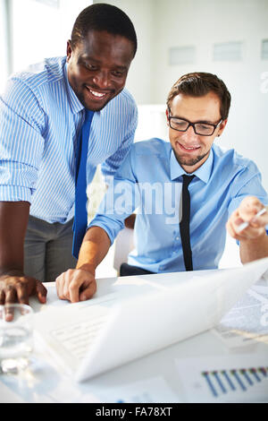 Zwei hübsche Geschäftsleute arbeiten zusammen an einem Projekt sitzen an einem Tisch im Büro Stockfoto