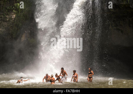 Touristen genießen ein Bad im Tegenungan Wasserfall in der Nähe von Ubud, Bali, Indonesien Stockfoto