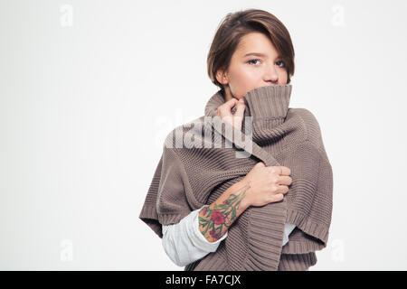 Nachdenklich traurige junge Frau mit Tatoo Lipd hinter Strickjacke über weißem Hintergrund ausblenden Stockfoto