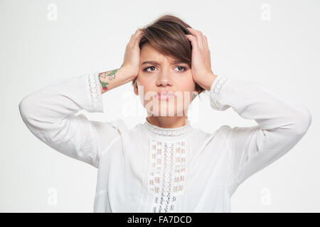 Depressive traurige junge Frau mit kurzen Haarschnitt halten Kopf mit Händen und mit Kopfschmerzen auf weißem Hintergrund Stockfoto