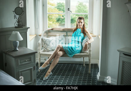 Hübsche Brünette Dame sitzt auf der Bank Peddigrohr Stockfoto