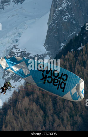 Tandempilot Paragliding geben sein Beifahrer einen Nervenkitzel durch Ausführen eines teilweisen Flügels über vor Gletscher und Wald. Stockfoto