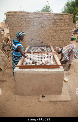 Frauen in Burkina Faso Sourou Provinz, habe ein kleines Geschäft des Rauchens und Verkauf von Fischen. Stockfoto