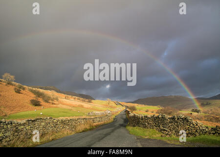 Ambelside, Cumbria, UK. 23. Dezember 2015. Großbritannien Wetter. Ein schöner Regenbogen erscheint kurz über die Straße, bekannt als "The Struggle" vor den Toren Ambelside in den Lake District National Park. Bildnachweis: Gary Telford/Alamy Live News Stockfoto