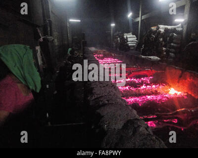 Quezon City, Philippinen. 23. Dezember 2015. Philippinische Arbeiter behandeln gebratenes Schwein gekocht in Bambus Rotiserries bei Vorort Quezon City, östlich von Manila, Philippinen. Gebratenes Schwein, genannt "Lechong Baboy" oder einfach "Lechon" ist eine beliebte Delikatesse während der Weihnachtszeit in den Philippinen. Das Land feiert die längste Weihnachtszeit in der Welt, die bereits im September beginnt. © Richard James M. Mendoza/Pacific Presse/Alamy Live-Nachrichten Stockfoto