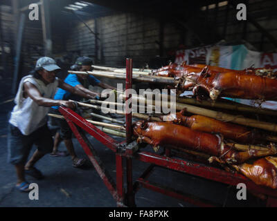 Quezon City, Philippinen. 23. Dezember 2015. Philippinische Arbeiter tragen gebratenes Schwein zu einem nahe gelegenen Restaurant im Vorort Quezon City, östlich von Manila, Philippinen. Gebratenes Schwein, genannt "Lechong Baboy" oder einfach "Lechon" ist eine beliebte Delikatesse während der Weihnachtszeit in den Philippinen. Das Land feiert die längste Weihnachtszeit in der Welt, die bereits im September beginnt. © Richard James M. Mendoza/Pacific Presse/Alamy Live-Nachrichten Stockfoto