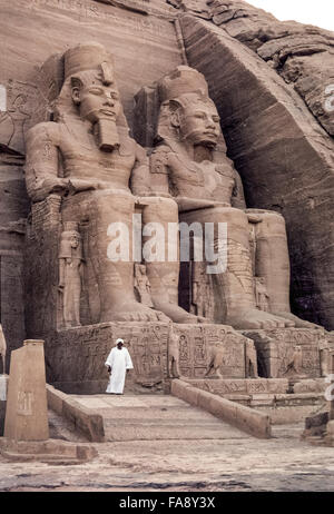 Eine ägyptische Altertümer Wache steht vor zwei der vier Kolossalstatuen des Pharaos Ramses II, die den Eingang zum großen Tempel in Abu Simbel, Ägypten, in Nordafrika zu dominieren. Der Tempel wurde im 13. Jahrhundert v. Chr. entlang der Westbank des Flusses Nil von einem Berg Fels geschnitzt. Als Nil Hochwasser infolge Bau des Assuan-Staudamms drohten, Tauchen Sie den Tempel in den 1960er Jahren, war es in große Stücke geschnitten und dann auf neue Website, die höher und weiter zurück vom Fluss wurde rekonstruiert. Diese bemerkenswerte Bewegung erforderlichen fünf Jahre 3000 Arbeiter und $ 42 Millionen. Stockfoto