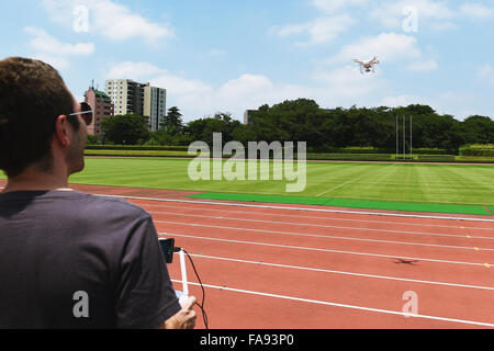 Kaukasischen Mann fliegen Quadcopter in einem Stadion Stockfoto