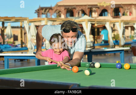 Kleines Mädchen mit Vater Billard spielen Stockfoto