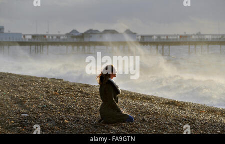 Brighton, Sussex UK 24. Dezember 2015 - eine junge Frau beobachtet die Wellen in Brighton Beach, wie Sturm Eva Großbritannien mit Stürme und Winde mit Böen von bis zu 80 km/h Credit hits: Simon Dack/Alamy Live News Stockfoto