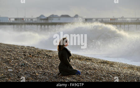 Brighton, Sussex UK 24. Dezember 2015 - eine junge Frau beobachtet die Wellen in Brighton Beach, wie Sturm Eva Großbritannien mit Stürme und Winde mit Böen von bis zu 80 km/h Credit hits: Simon Dack/Alamy Live News Stockfoto