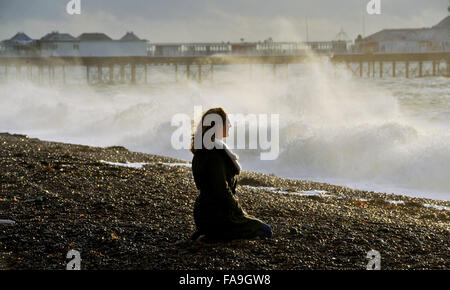 Brighton, Sussex UK 24. Dezember 2015 - eine junge Frau beobachtet die Wellen in Brighton Beach, wie Sturm Eva Großbritannien mit Stürme und Winde mit Böen von bis zu 80 km/h Credit hits: Simon Dack/Alamy Live News Stockfoto