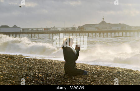 Brighton, Sussex UK 24. Dezember 2015 - eine junge Frau beobachtet die Wellen in Brighton Beach, wie Sturm Eva Großbritannien mit Stürme und Winde mit Böen von bis zu 80 km/h Credit hits: Simon Dack/Alamy Live News Stockfoto