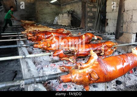 Manila, Philippinen. 24. Dezember 2015. Arbeiter der Brgy. Laloma in Quezon City sind immer beschäftigt, um die bestellten Lechon Baboy (gebratenes Schweinefleisch) für die Feier der Noche Buena kochen, nach der Lechonero (gebratenes Schweinefleisch kochen) kochen sie gebratene Schweinefleisch von 2 bis 3 Stunden. und es hängt von der Größe und sie noch in traditioneller Weise oder manuelle Drehung des Schweinefleisches Sicherstellung die Qualität von geröstetem Schweinefleisch kochen. Bildnachweis: Gregorio B. Dantes/Pacific Press/Alamy Live-Nachrichten Stockfoto