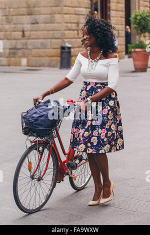 Lockiges Haar Mode Frau mit dem roten Fahrrad Stockfoto