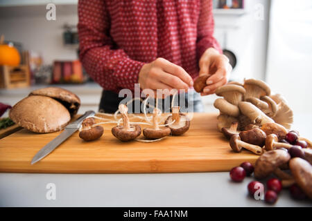 Eine elegante Frauenhand arbeiten an Pilzen aneinanderreihen, wie sie eine Herbst-Mahlzeit bereitet. Bald wird das reichen, erdige Aroma von geröstetem Gemüse und Früchte fallen die Luft füllen. Stockfoto